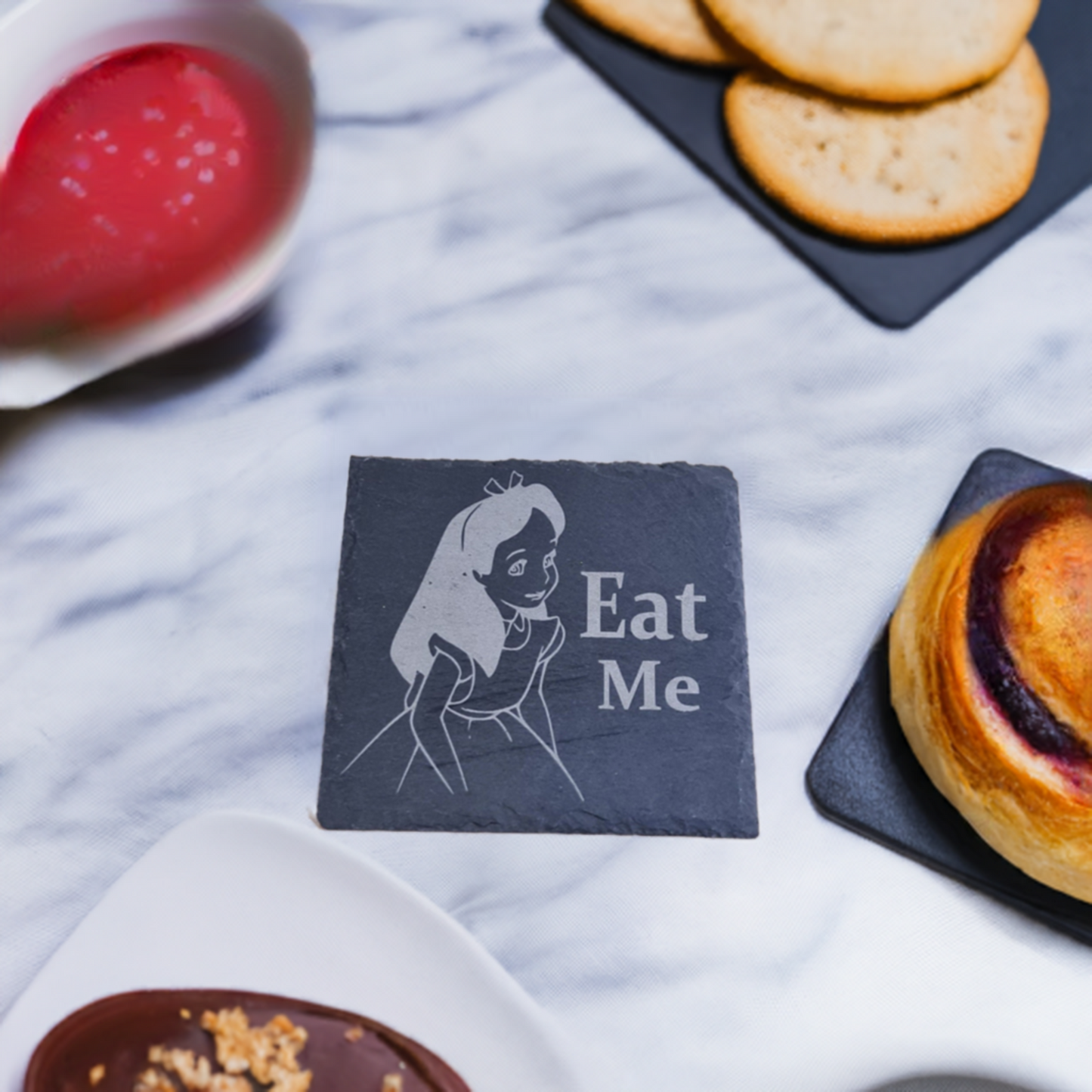 alice in wonderland coaster on a marble surface with cakes