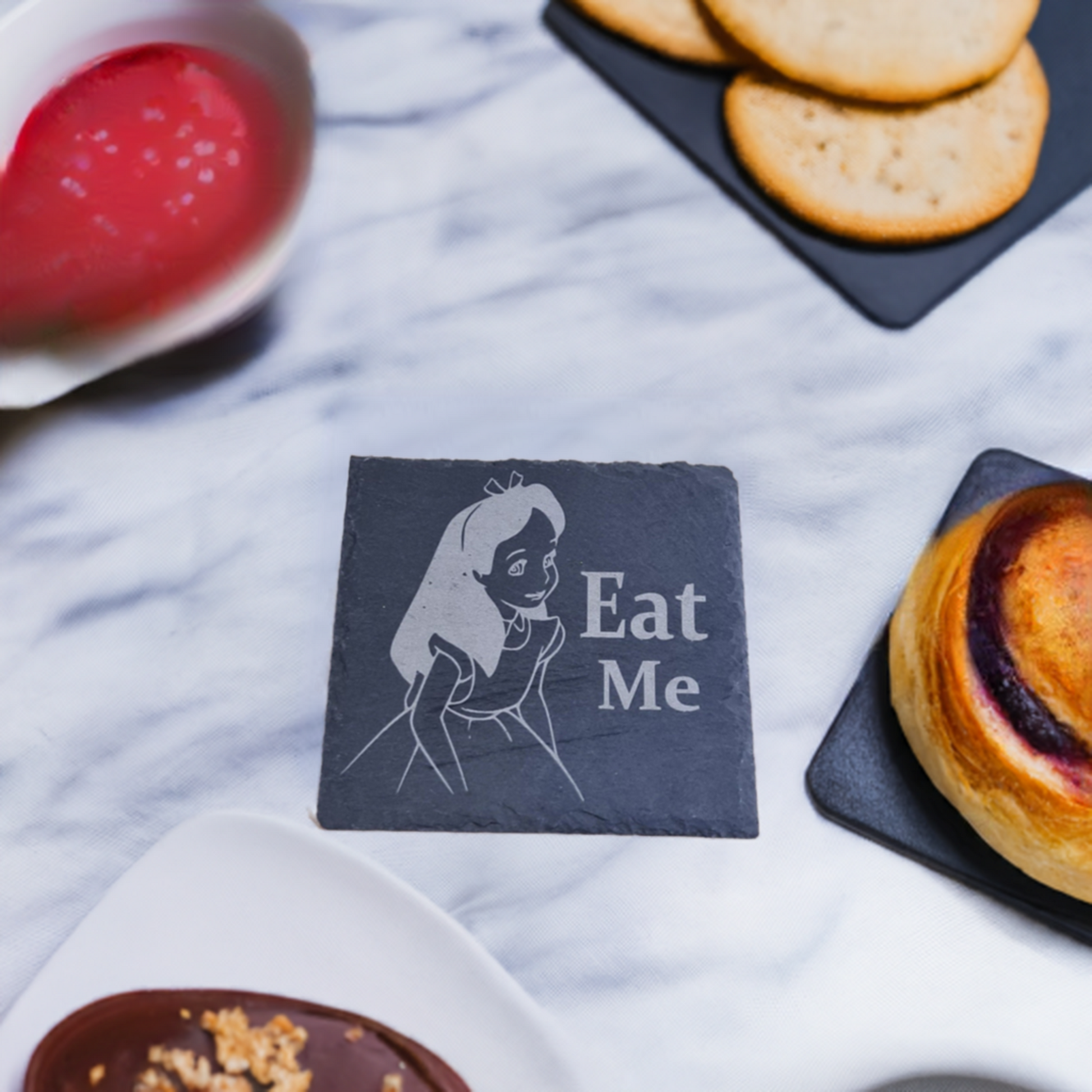 alice in wonderland coaster  on a marble surface with cakes