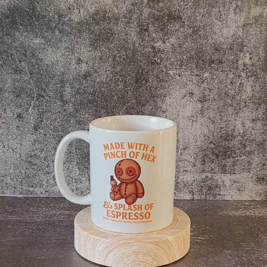 White ceramic mug with voodoo doll and pinch of hex espresso design.