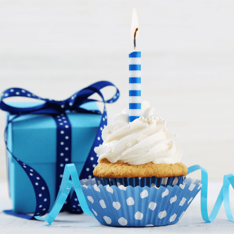 birthday cup cake with candle and blue gift on a white background