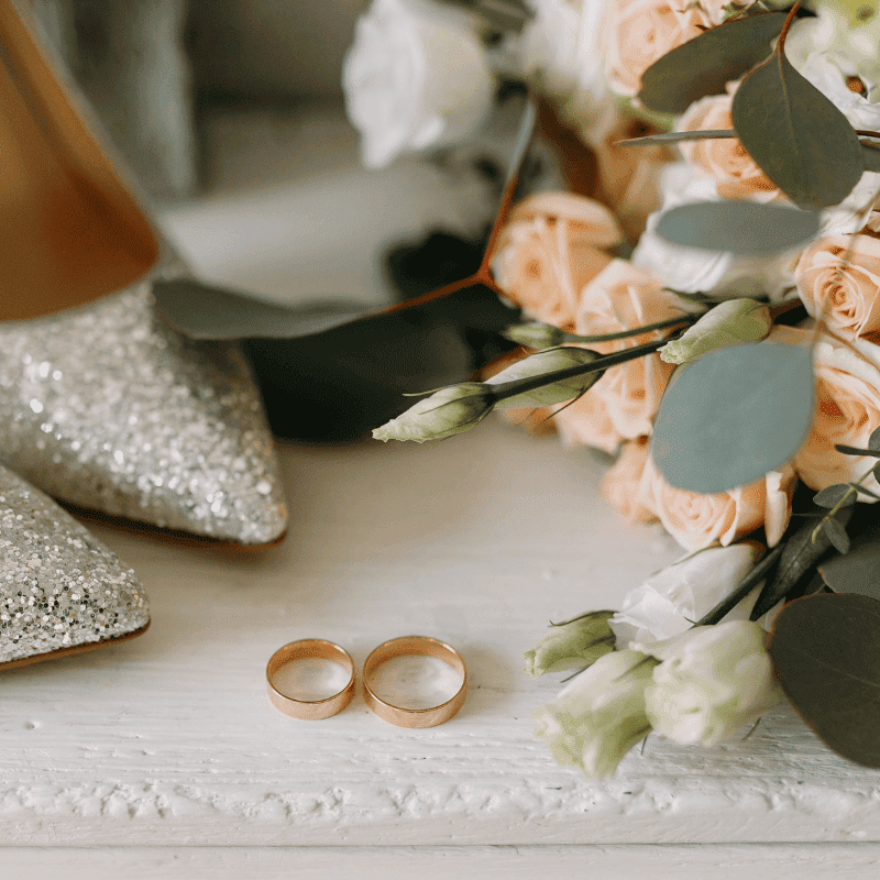 wedding flowers and brides shows with 2 gold band rings on a light background