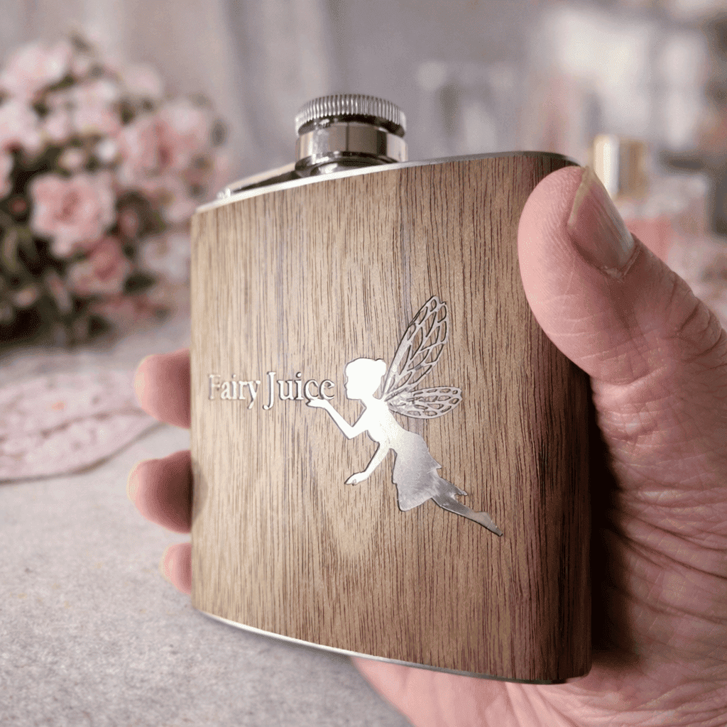 fairy engraved wooden 6oz hip flask on a pink background held in a hand