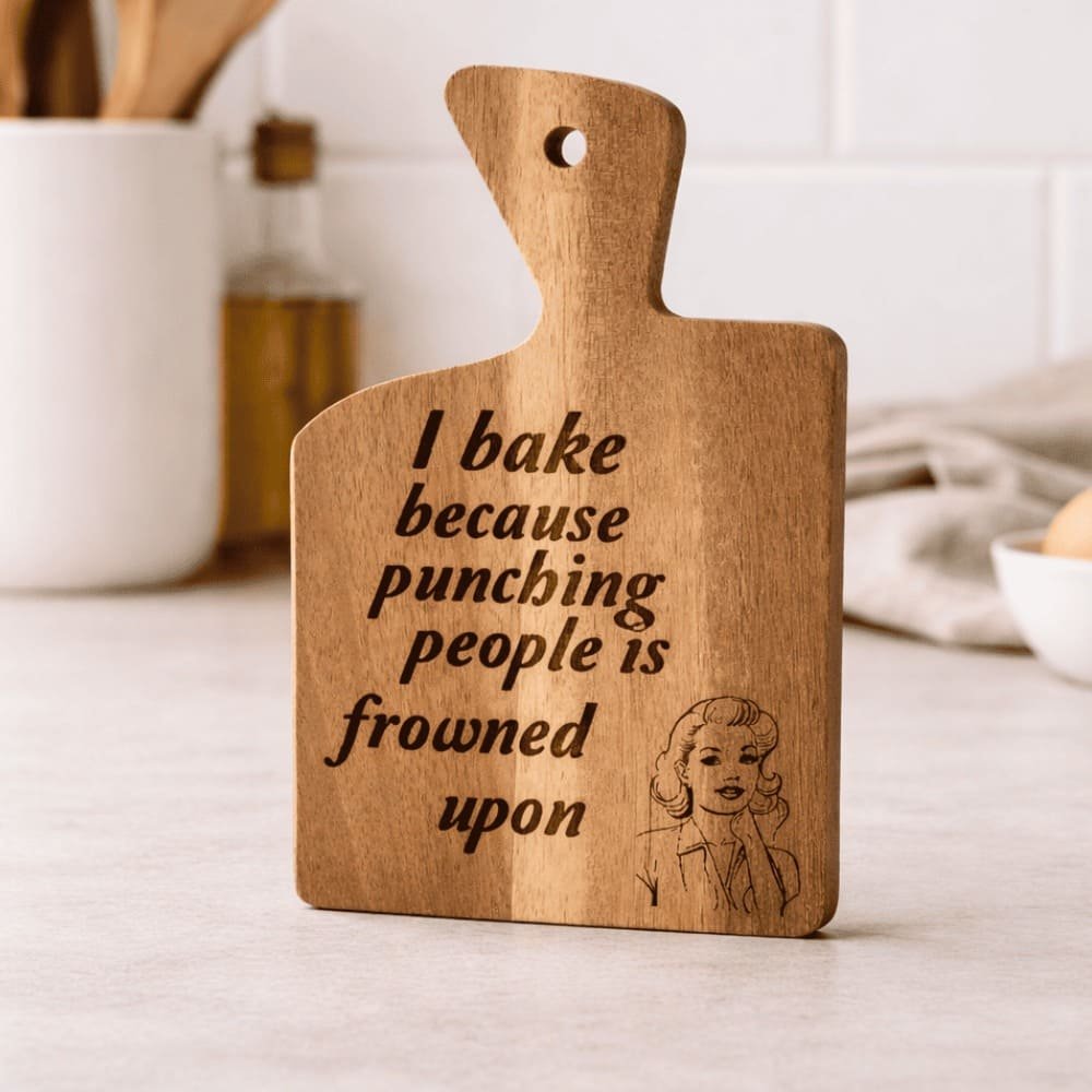 Engraved wooden chopping board featuring a funny baking quote and illustrated design, a unique personalised-style gift for the kitchen and home.